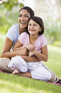 Mother and daughter outdoors in park smiling (selective focus)