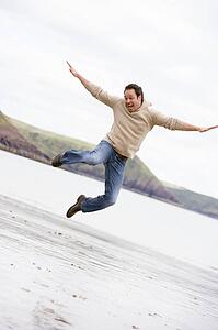 Man jumping on beach smiling