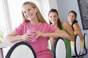 Three young women having a cold drink in a cafeteria