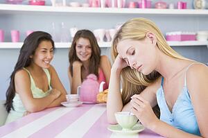 Young woman with a hangover sitting at a table with two friends