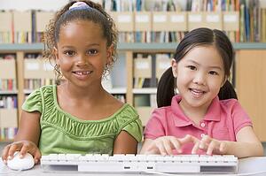 Two students in class at computer keyboard