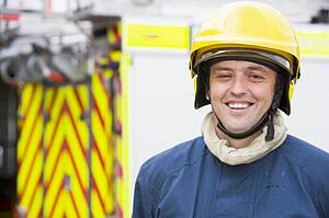 Fireman standing by fire engine wearing helmet