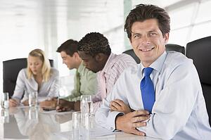 Four businesspeople in a boardroom smiling