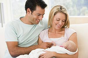 Couple in living room with baby smiling