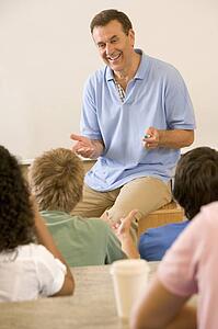 Teacher giving lecture to students in classroom (selective focus)
