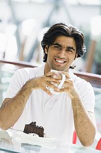 Man at restaurant eating dessert and smiling (selective focus)