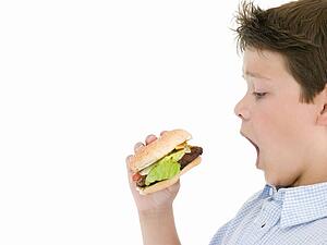 Young boy eating cheeseburger