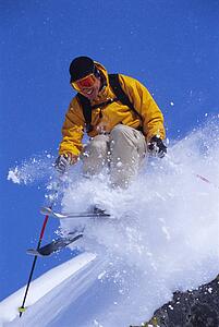 Skier jumping on snowy hill and smiling