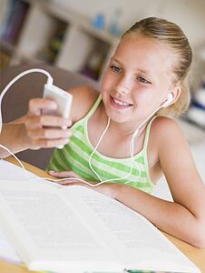 Young Girl Distracted From Her Homework, Playing With An MP3 Player