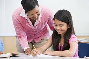 Student in class writing with teacher