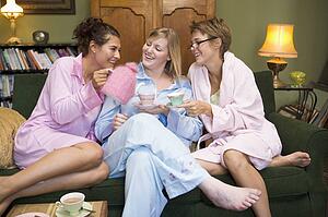 Young woman sitting on sofa at home drinking tea
