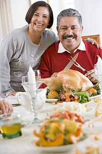 Woman With Her Arm Around Her Husband, Who Is Getting Ready To Carve A Turkey