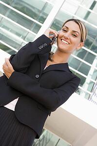 Businesswoman standing outdoors on cellular phone smiling
