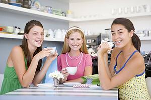 Three young woman sitting at a table and drinking tea