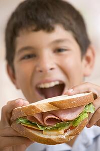 Young boy eating sandwich smiling