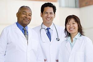 Three Doctors Standing Outside A Hospital