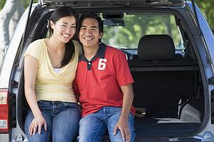 Couple sitting in back of van smiling