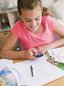 Young Girl Distracted From Her Homework, Playing With A Cellphone