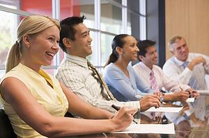 Five businesspeople at boardroom table smiling