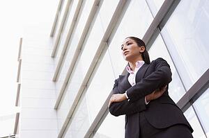 Businesswoman standing outdoors by building (high key/selective focus)