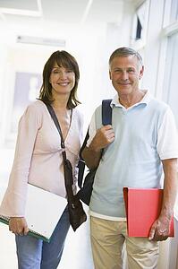 Man and woman standing in corridor with books (high key)