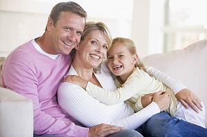 Family sitting in living room smiling