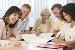 Five adult students studying at table (depth of field)