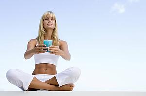 Woman sitting and meditating outdoors while holding a candle