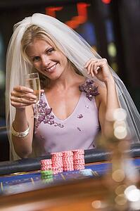 Woman in bridal veil in casino playing roulette and smiling (selective focus)