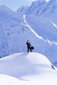 Businessman outdoors on snowy mountain using cellular phone