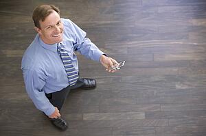 Businessman standing indoors holding cellular phone smiling