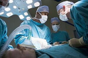Three Surgeons Operating On A Patient