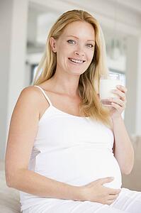 Pregnant woman with glass of milk smiling