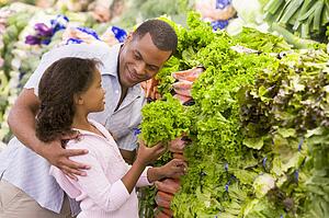 Father and daughter shopping for lettuce at a grocery store