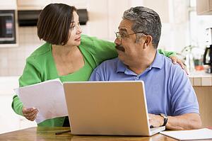 Couple in kitchen with laptop and paperwork