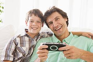 Man and young boy with handheld game smiling