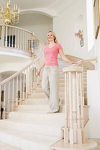 Woman coming down staircase in luxurious home smiling