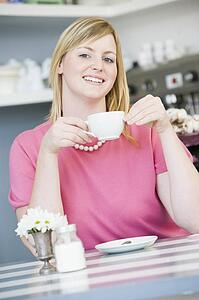Young woman sitting at a table drinking tea