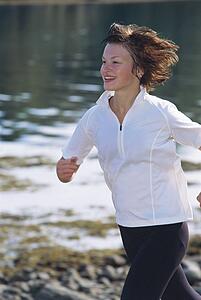Woman outdoors by a stream running and smiling (selective focus)