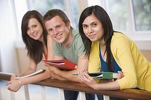 Three students in corridor leaning on railing (depth of field)