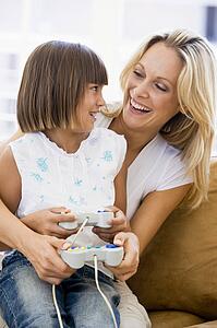 Woman and young girl in living room with video game controllers smiling