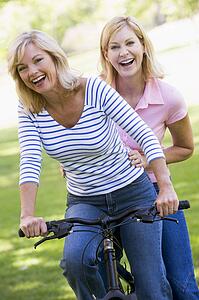Two friends on one bike outdoors smiling