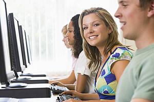 Four people sitting at computer terminals (selective focus/high key)