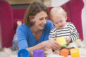 Mother in living room playing with baby smiling