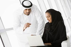 Two people indoors with laptop smiling (high key/selective focus)