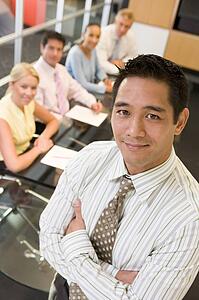 Businessman with four businesspeople at boardroom table in background