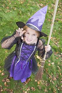 Young girl outdoors in witch costume on Halloween