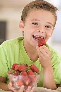 Young boy eating strawberries in living room smiling