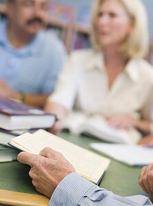 Three people sitting in library with books and notepads (selective focus)