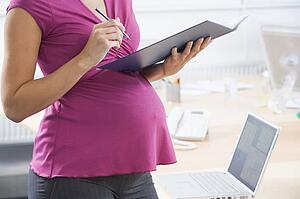 Pregnant woman at work writing in binder